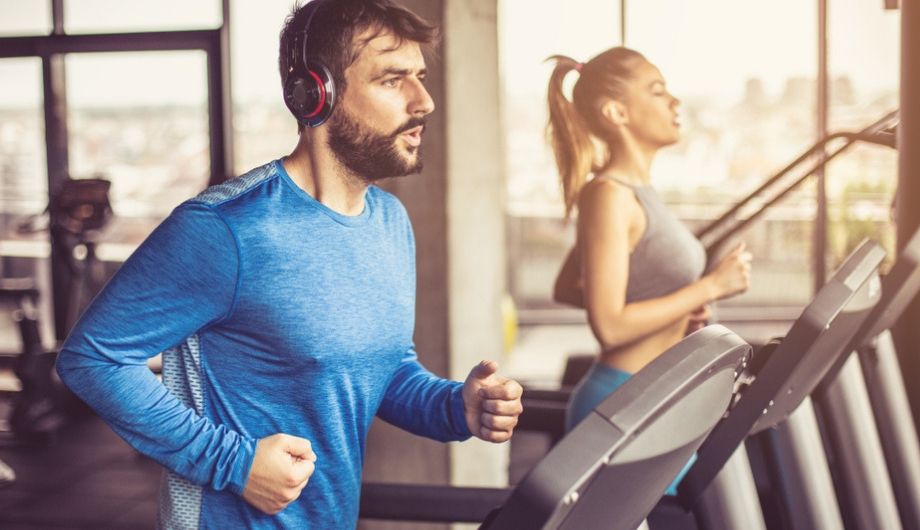 Couple with headphones working exercise on treadmill