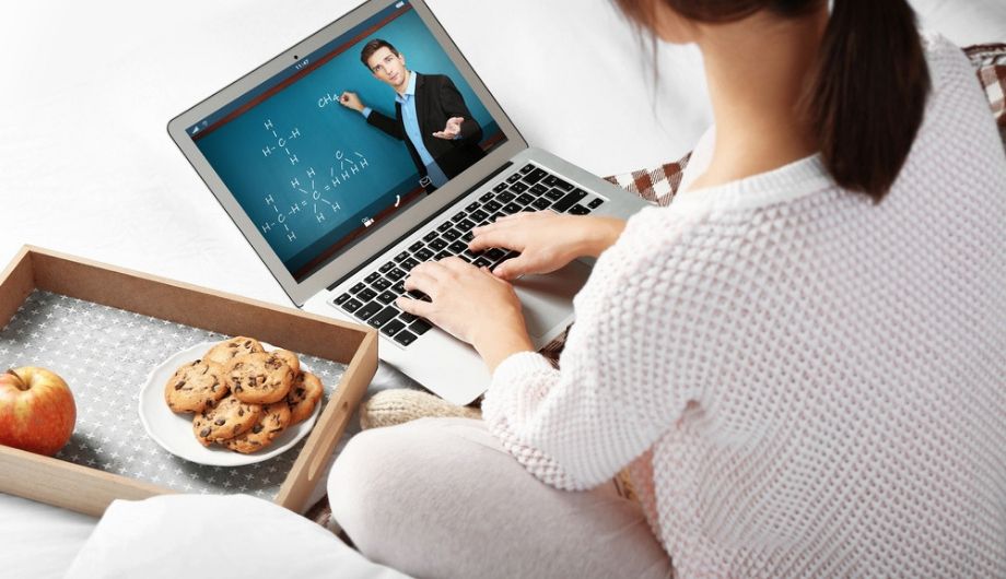 Woman video conferencing with tutor on laptop at home